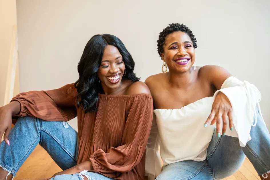 Two women laughing and sitting on the floor