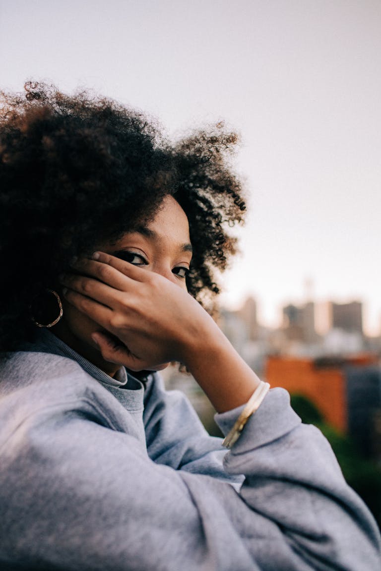 A woman with afro hair enjoying a casual moment in an urban setting.