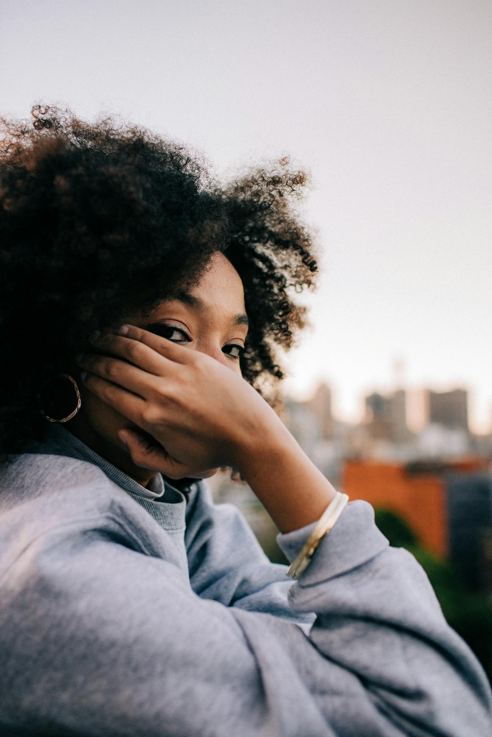 A woman with afro hair enjoying a casual moment in an urban setting.