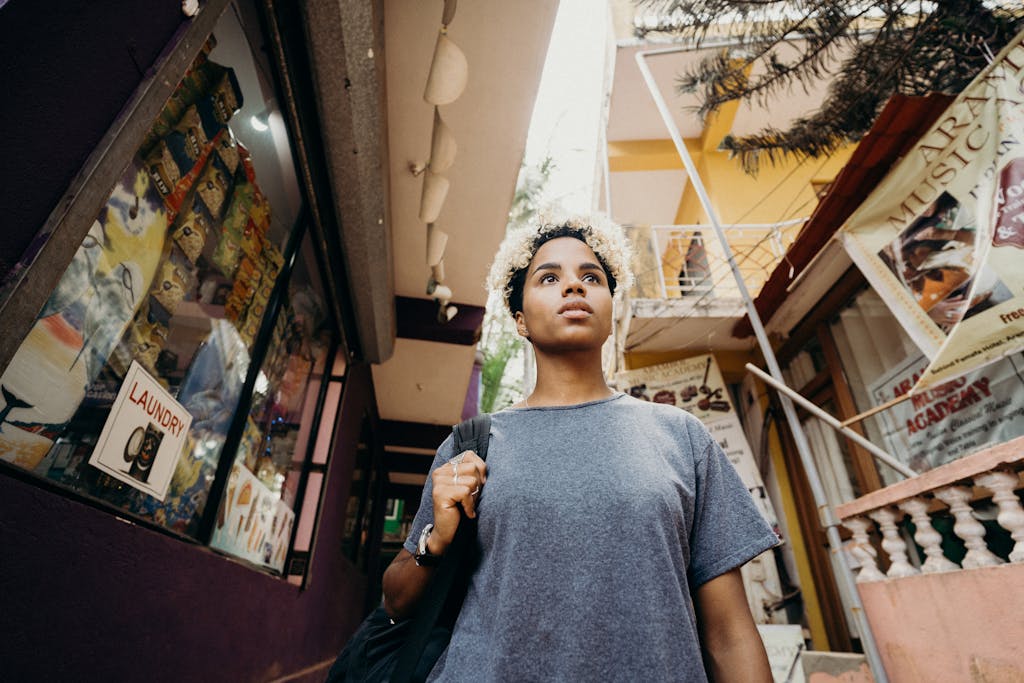 Portrait of a young woman with curly hair walking through a vibrant street in urban setting, looking around curiously.