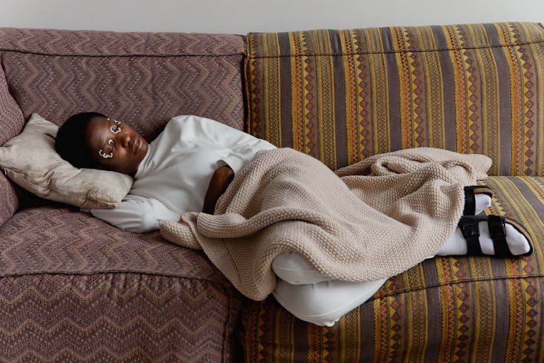 Black woman lying on a couch under a blanket, representing ADHD paralysis