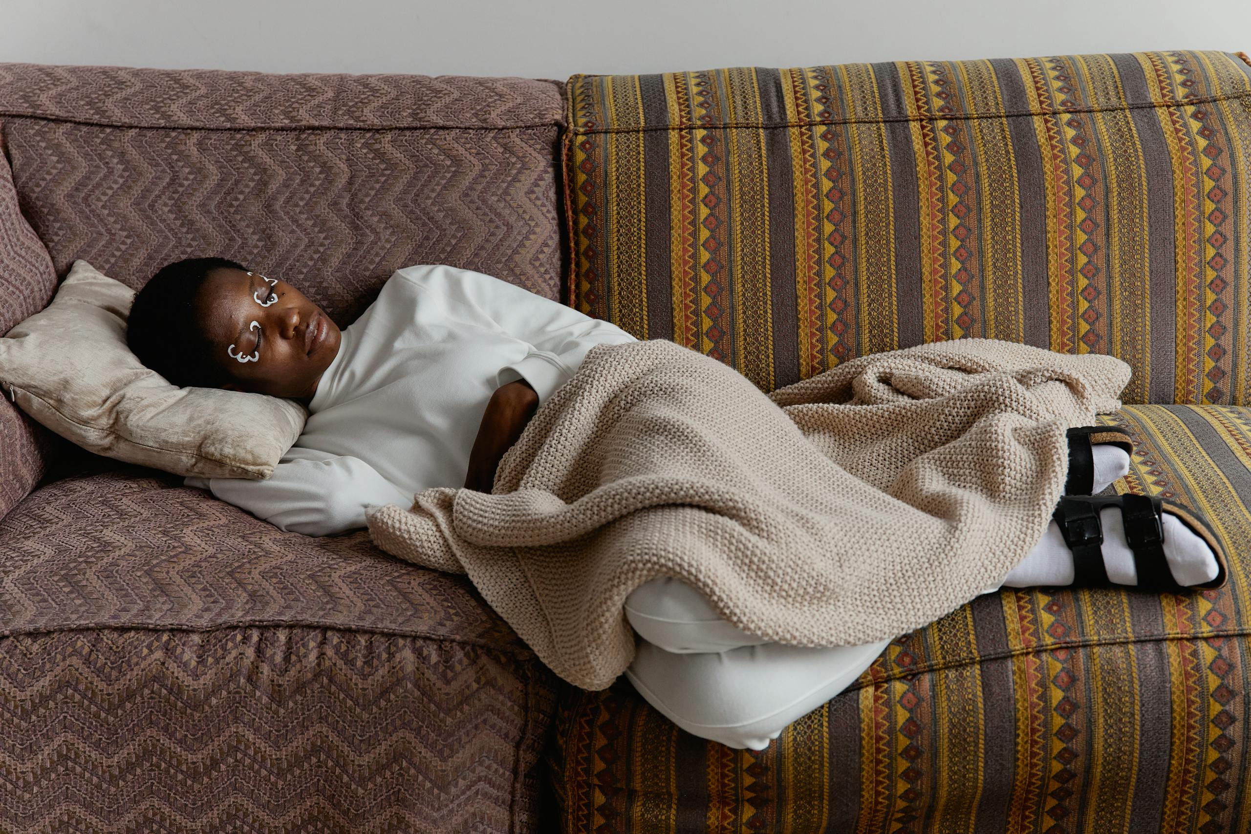 Black woman lying on a couch under a blanket, representing ADHD paralysis