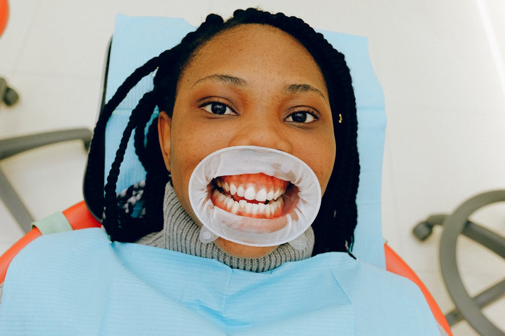 Close-up of a woman during a dental exam with a cheek retractor, wondering why do I hate brushing my teeth.