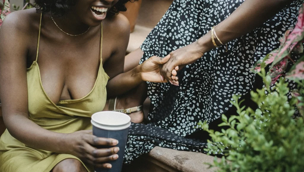 Two Black women enjoying laughter and coffee outdoors, reflecting the lived experience of ADHD in late-diagnosed women.