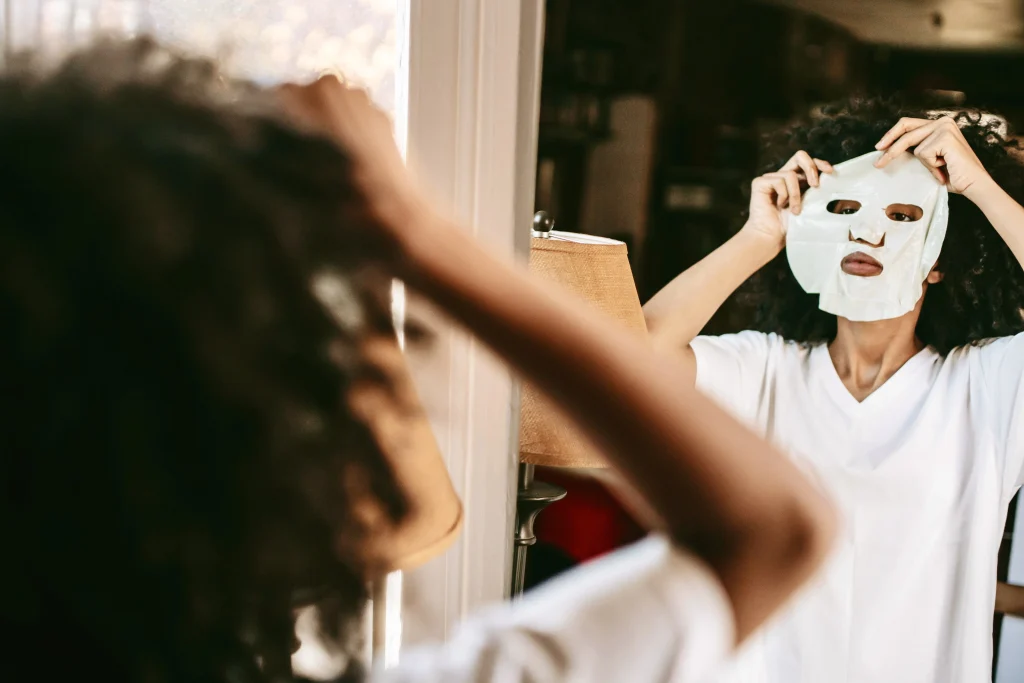 A Black woman applying a "Strong Black Woman" mask to hide symptoms of Inattentive ADHD and executive dysfunction.