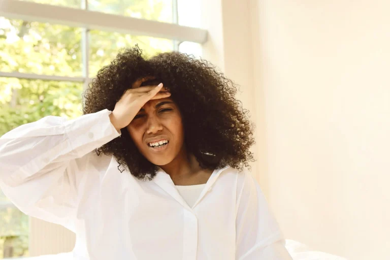 A woman holding her head in distress, illustrating how ADHD can feel like internal noise and sensory overwhelm rather than physical movement.
