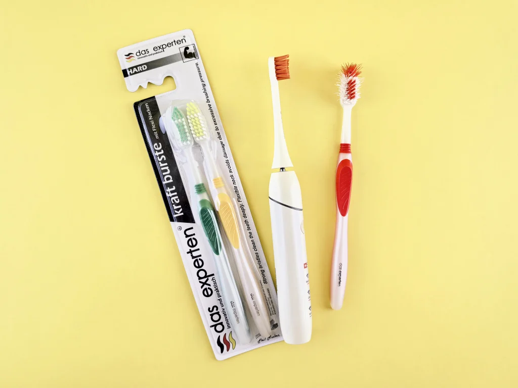 Manual and electric toothbrushes on a yellow background